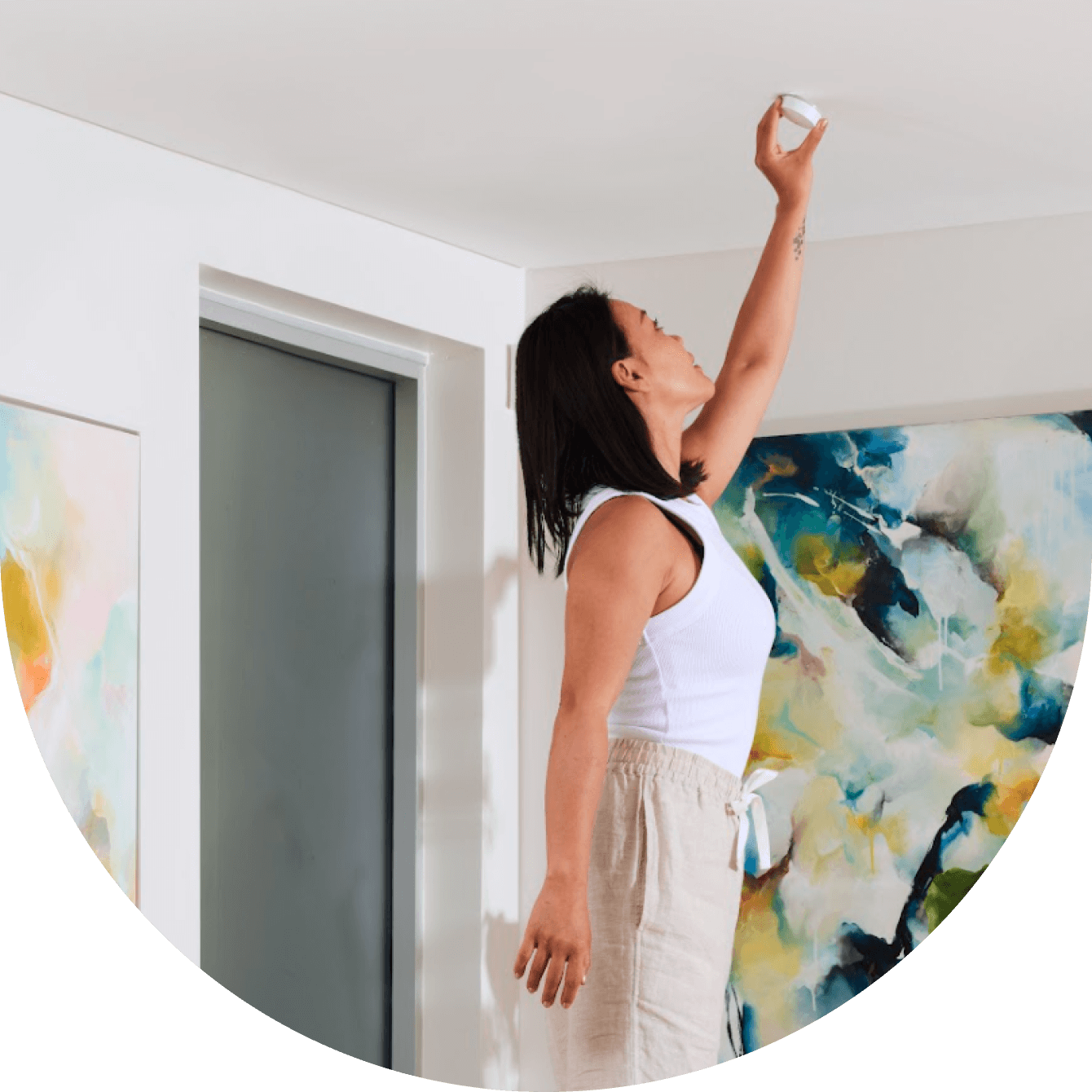 woman installing sensor on the ceiling